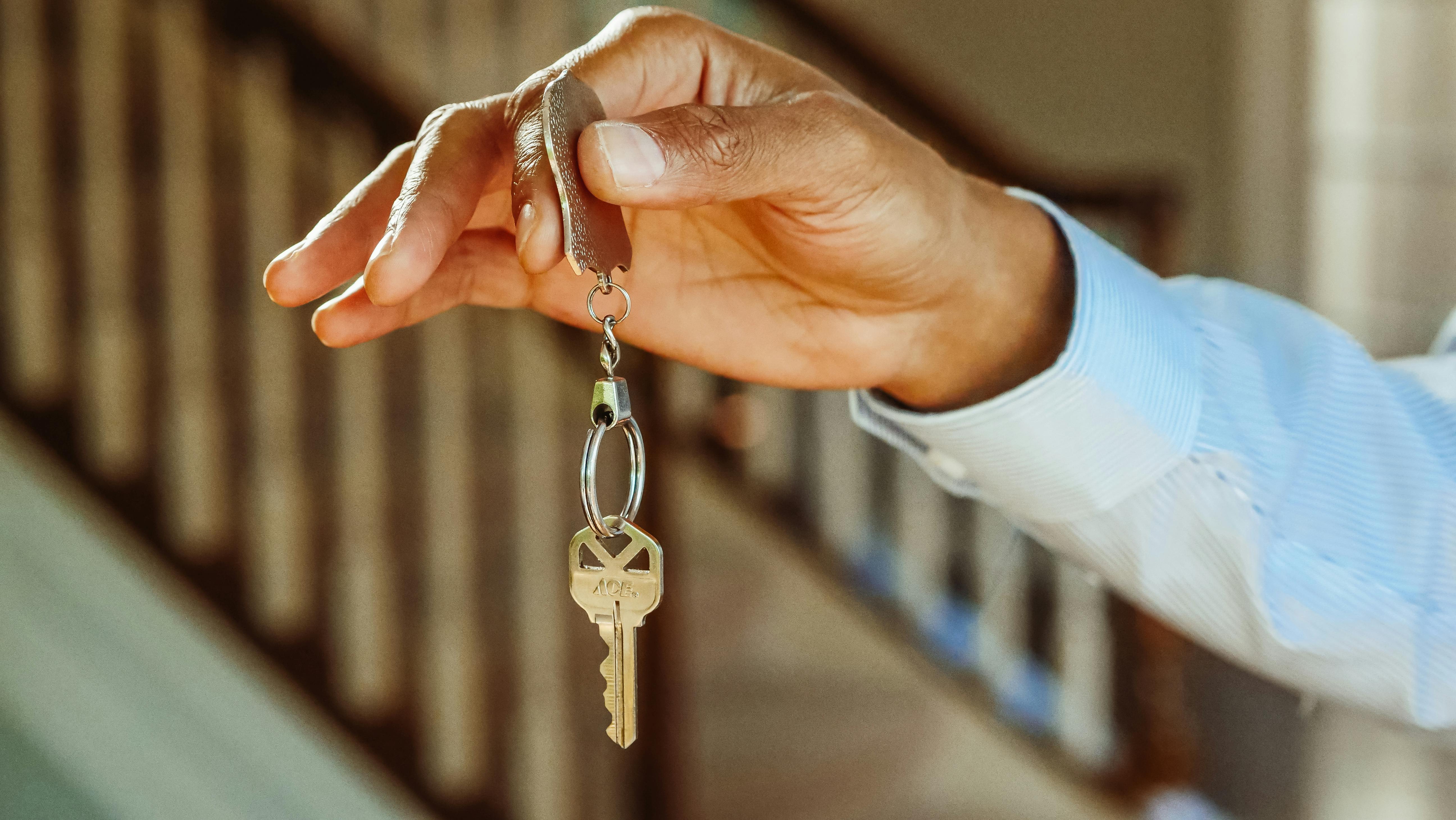 A hand handing over a house key.